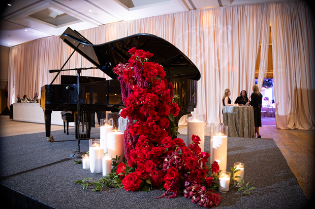 The Heart Ball ballroom with a grand piano with a big bouquet of red roses