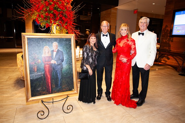 group photo of guests of the heart ball in front of a oil portrait